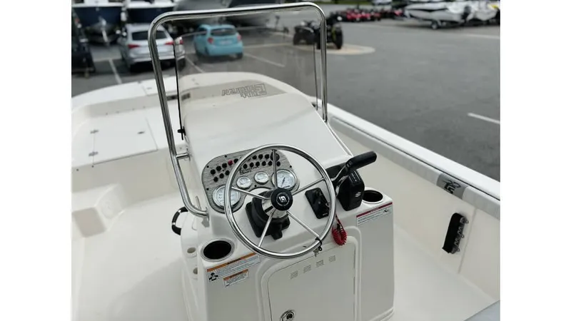 Slide: The Image of 2025 Carolina Skiff 21 LS boat console with steering wheel and controls in a parking lot. - 11