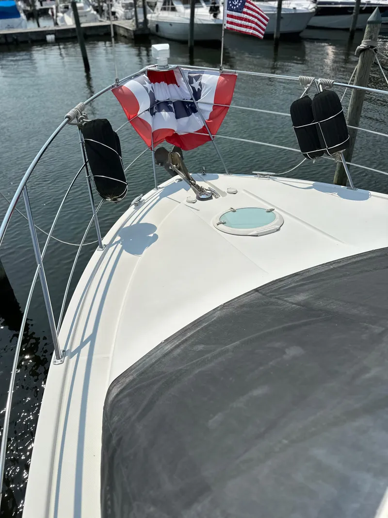 Slide: The Image of 2005 Carver 366 Motor Yacht bow with flag and docked boats in background. - 10