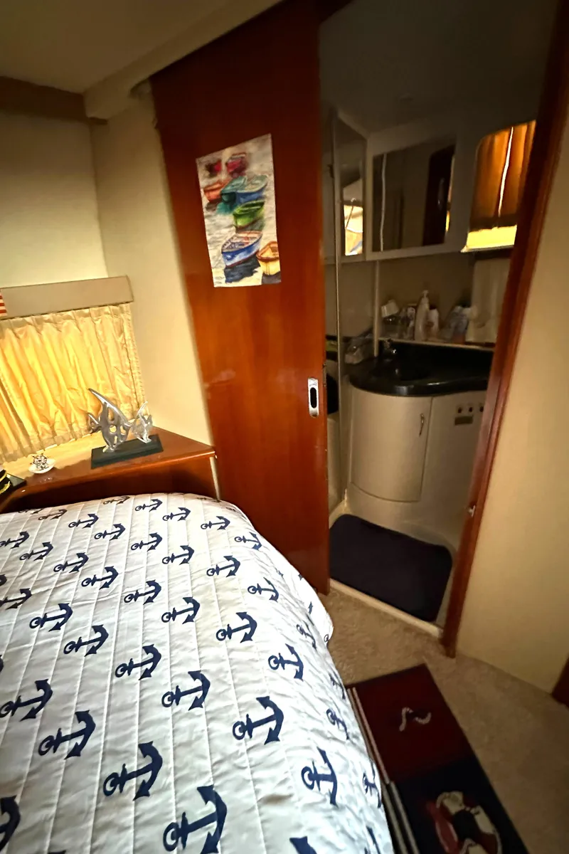Slide: The Image of 2005 Carver 366 Motor Yacht interior with nautical-themed bedding and compact bathroom. - 26