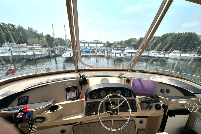 Slide: The Image of 2005 Carver 366 Motor Yacht helm view at marina with boats and bridge in background. - 28