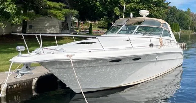 The Image of 1999 Sea Ray 330 Sundancer boat docked by lush greenery. - 0