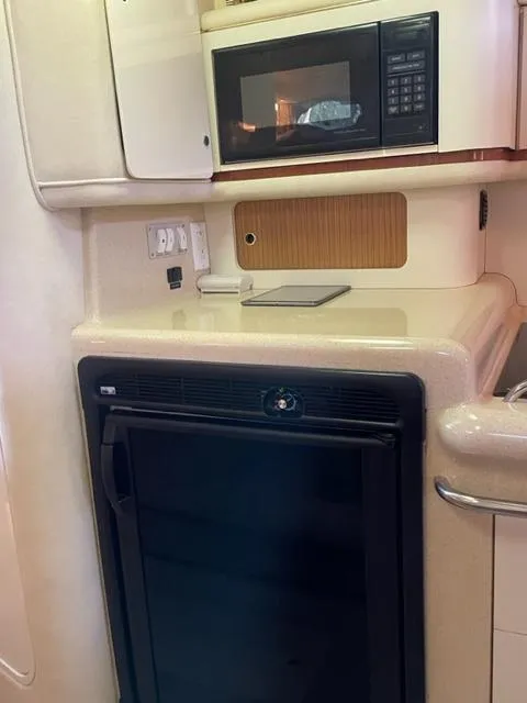 Slide: The Image of 1999 Sea Ray 330 Sundancer interior kitchen with microwave, sink, and seating area. - 6