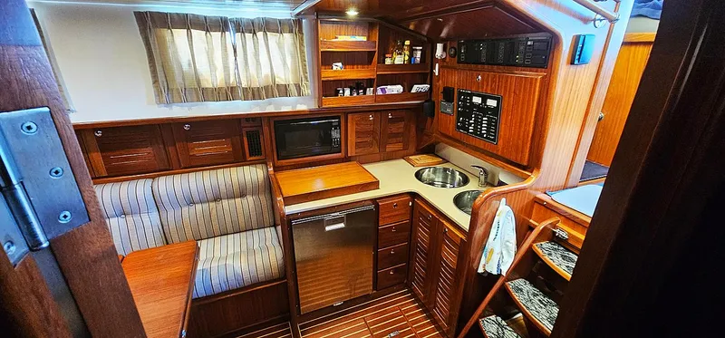 Slide: The Image of Interior of a 2003 Menorquin 120 yacht, featuring kitchen and seating area. - 20