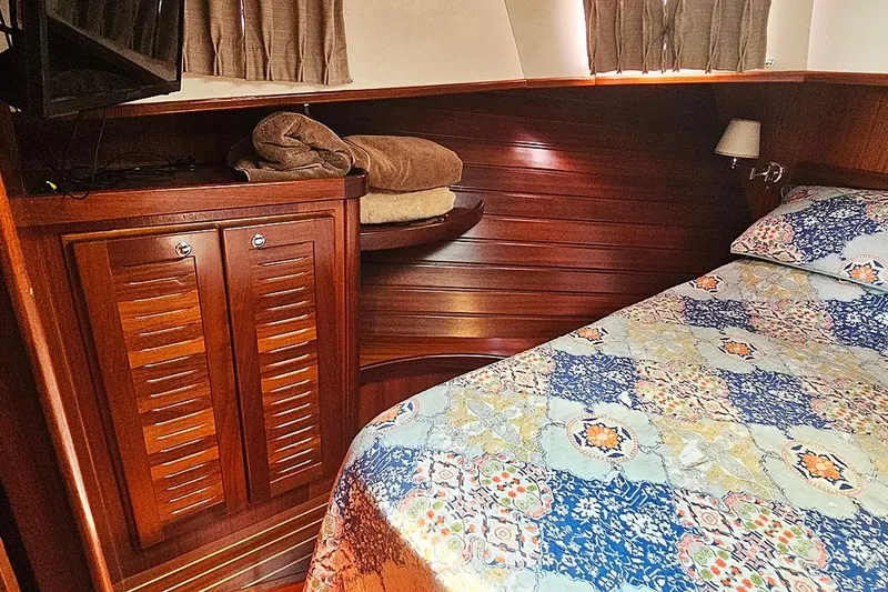 Slide: The Image of Cozy cabin interior of 2003 Menorquin 120 yacht with wooden finishes and patterned bedding. - 23