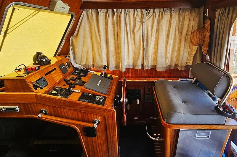 Slide: The Image of Interior of a 2003 Menorquin 120 boat, featuring a wooden helm and navigation equipment. - 8