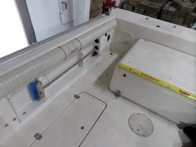 Slide: The Image of 1999 Sport-Craft 251 WA boat interior with storage compartments and cleaning brush. - 24