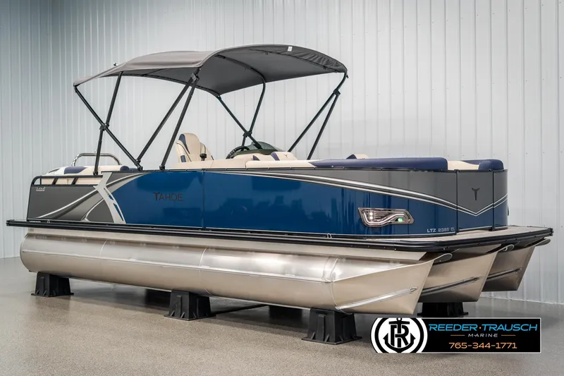 Slide: The Image of 2025 Tahoe LTZ EL pontoon boat with canopy in showroom, featuring sleek blue design. - 2