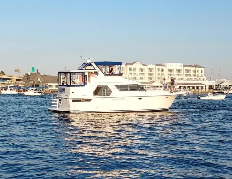 The Image of 1994 Carver 440 Aft Cabin Motor Yacht on water, with marina and buildings in background. - 0