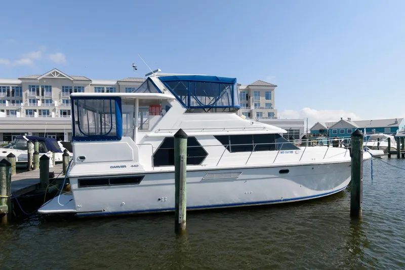 Slide: The Image of 1994 Carver 440 Aft Cabin Motor Yacht docked at marina, clear sky background. - 1