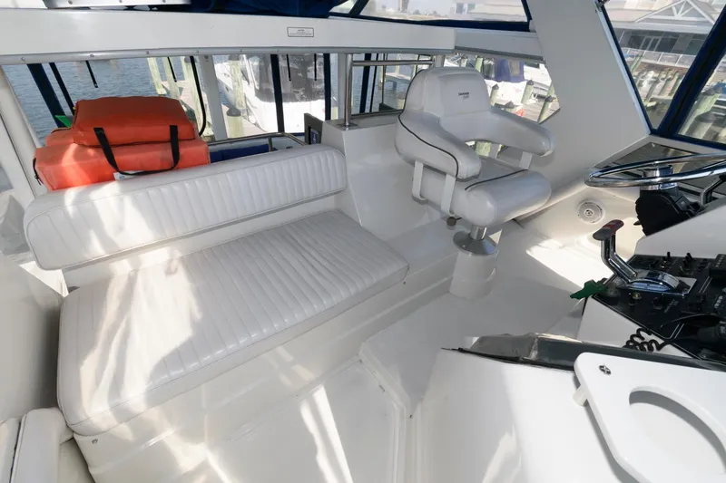 Slide: The Image of 1994 Carver 440 Aft Cabin Motor Yacht interior with white seating and helm station. - 11