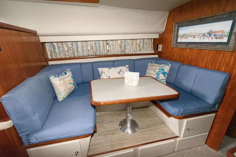 Slide: The Image of 1994 Carver 440 Aft Cabin Motor Yacht interior with blue cushioned seating and dining table. - 17