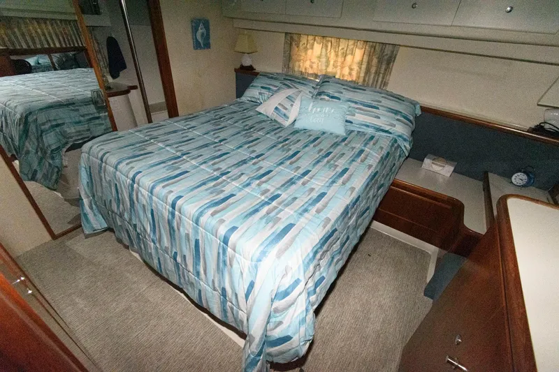 Slide: The Image of 1994 Carver 440 Aft Cabin Motor Yacht bedroom with blue-striped bedding. - 18