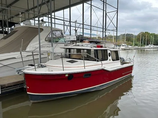 Slide: The Image of 2023 Ranger Tugs R23 boat docked in marina, red hull, overcast sky. - 1