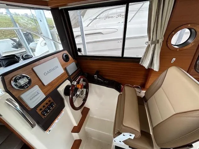 Slide: The Image of 2023 Ranger Tugs R23 helm with Garmin navigation, beige seating, and wood accents. - 17