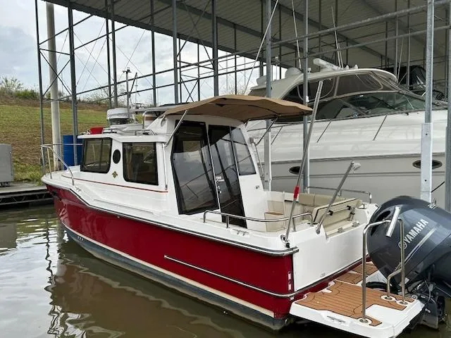 Slide: The Image of 2023 Ranger Tugs R23 boat with red hull, docked under a covered marina. - 2