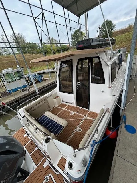 Slide: The Image of 2023 Ranger Tugs R23 boat docked, featuring spacious deck and seating area under a covered marina. - 6