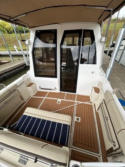 Slide: The Image of 2023 Ranger Tugs R23 boat interior with teak flooring and cushioned seating. - 7