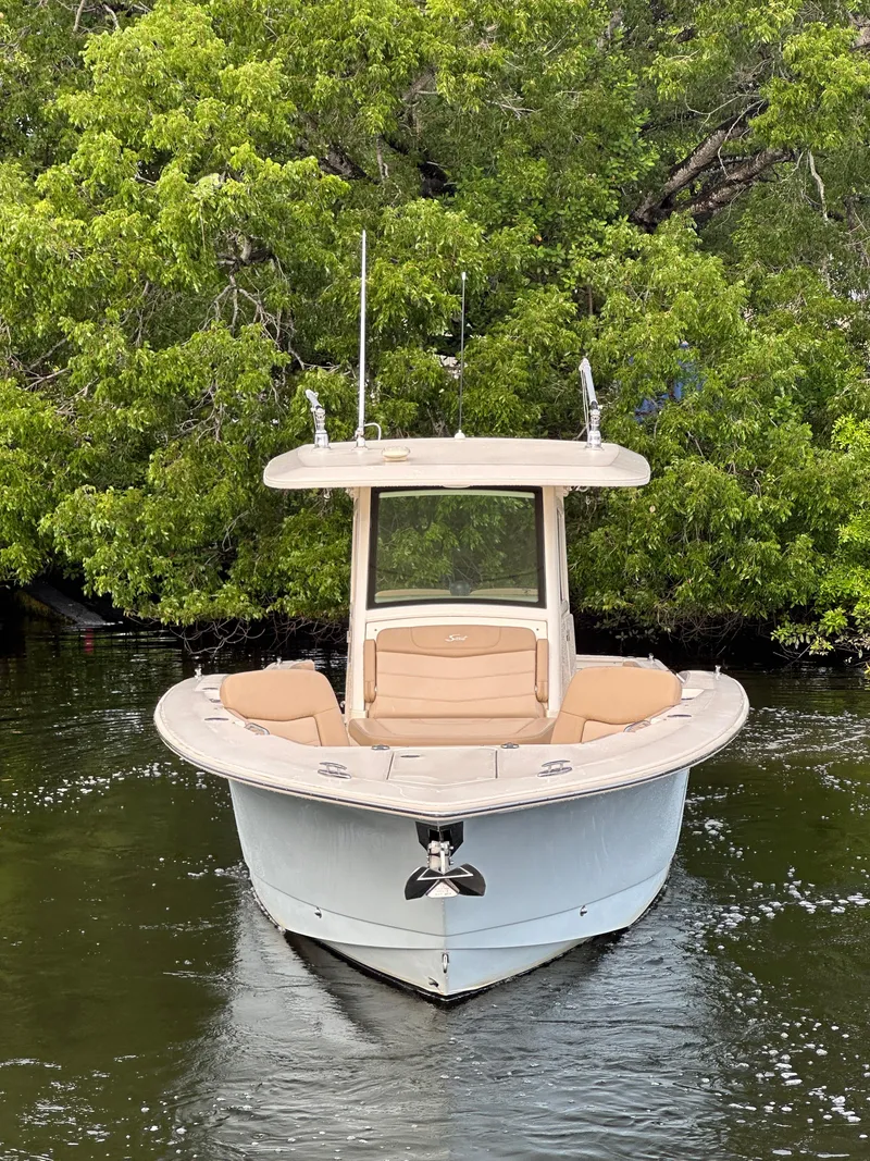 Slide: The Image of 2021 Scout 305 LXF boat on calm water, surrounded by lush greenery. - 11