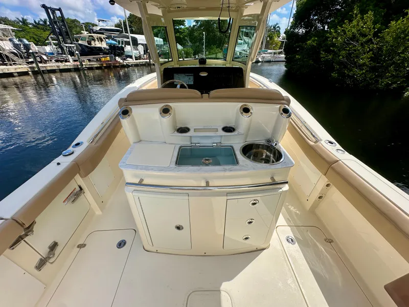Slide: The Image of 2021 Scout 305 LXF boat interior with sink and storage, docked by the water. - 5