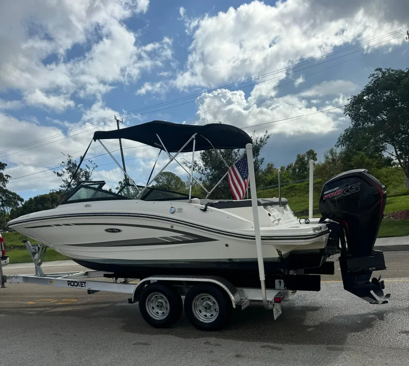 Slide: The Image of 2017 Sea Ray 19 SPX boat on trailer with American flag, parked under cloudy sky. - 7