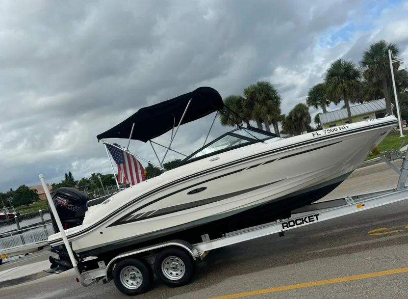 Slide: The Image of 2017 Sea Ray 19 SPX boat on trailer with American flag, parked near palm trees. - 9
