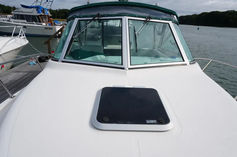 Slide: The Image of 2002 Pursuit 2865 Denali boat docked, featuring a sleek white deck and windshield. - 12