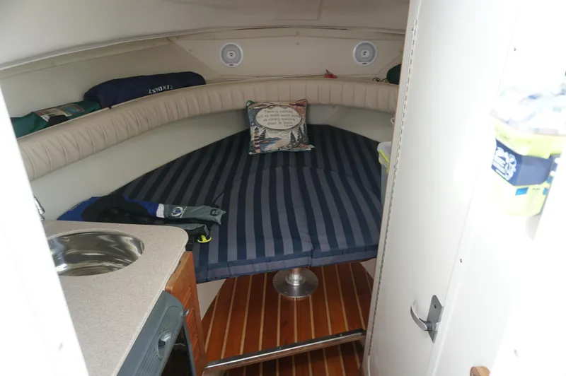 Slide: The Image of 2002 Pursuit 2865 Denali cabin interior with striped bedding and compact kitchenette. - 18