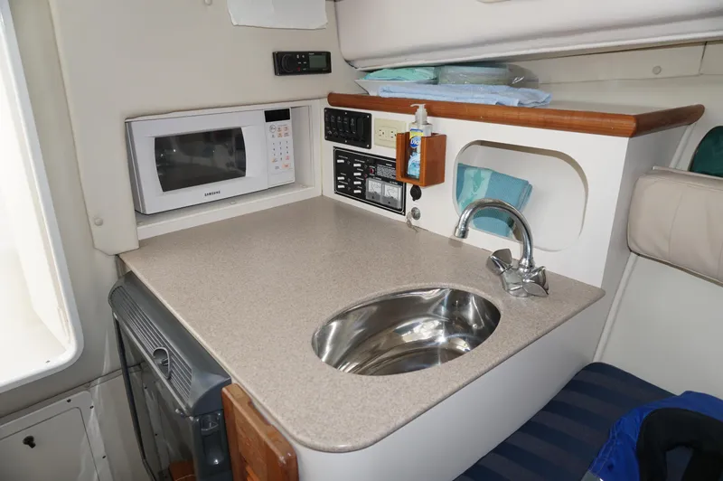Slide: The Image of Compact kitchen area in a 2002 Pursuit 2865 Denali boat with sink and microwave. - 19