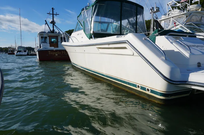 Slide: The Image of 2002 Pursuit 2865 Denali boat docked in a marina, surrounded by other vessels. - 2