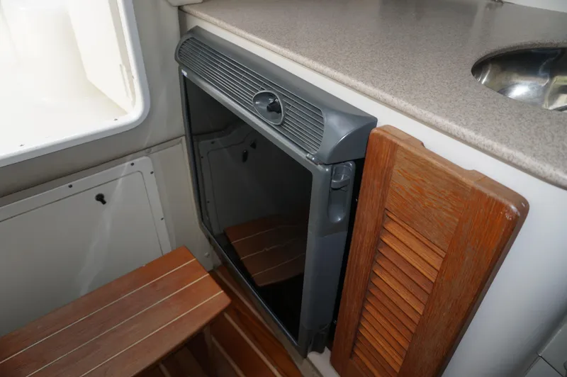 Slide: The Image of 2002 Pursuit 2865 Denali cabin interior with compact fridge and wooden accents. - 20