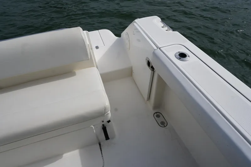 Slide: The Image of 2002 Pursuit 2865 Denali boat interior with white seating and storage, on water. - 5