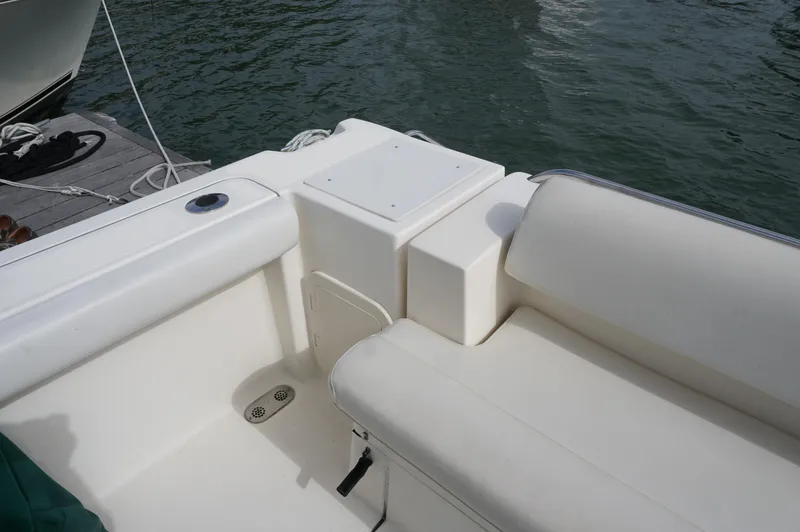 Slide: The Image of 2002 Pursuit 2865 Denali boat interior with white seating and dockside view. - 7