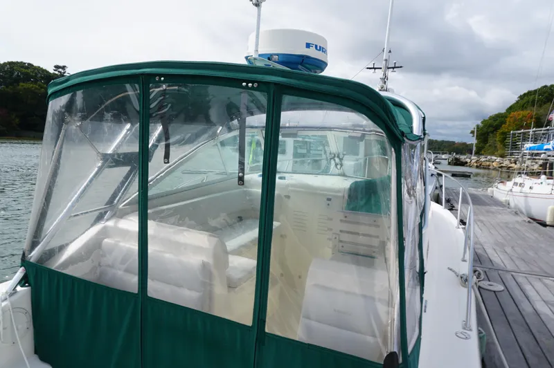 Slide: The Image of 2002 Pursuit 2865 Denali boat with green canopy docked by the water. - 8