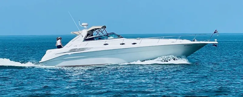 The Image of 1995 Sea Ray 450 Sundancer cruising on open water under clear blue skies. - 1