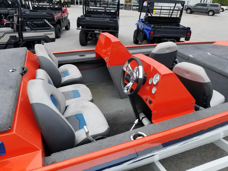 Slide: The Image of Custom 2012 welded boat with orange dashboard and gray seats, parked near utility vehicles. - 4