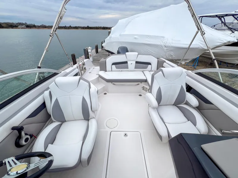 Slide: The Image of 2017 Four Winns HD220 OB boat interior with white seating, docked by the water. - 22