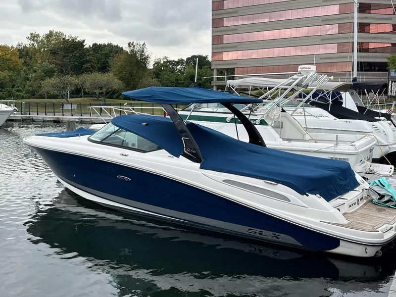 Slide: The Image of 2013 Sea Ray 270 SLX boat docked with blue cover and canopy. - 0