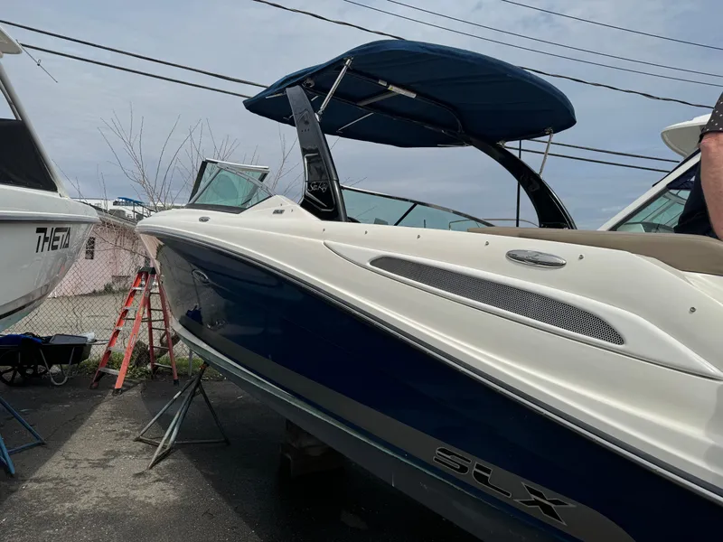 Slide: The Image of 2013 Sea Ray 270 SLX boat with blue hull and canopy, docked outdoors. - 2