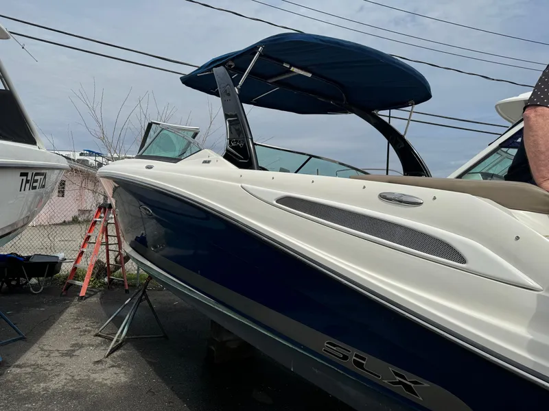 Slide: The Image of 2013 Sea Ray 270 SLX boat with blue hull and canopy, docked outdoors. - 31