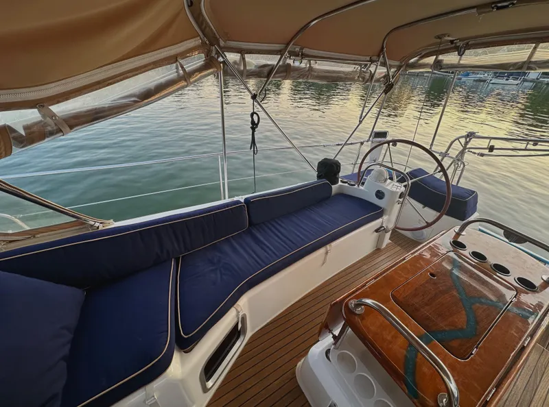 Slide: The Image of Luxurious Jeanneau Sun Odyssey 50 DS yacht cockpit with blue seating, wooden table, and scenic water view. - 13