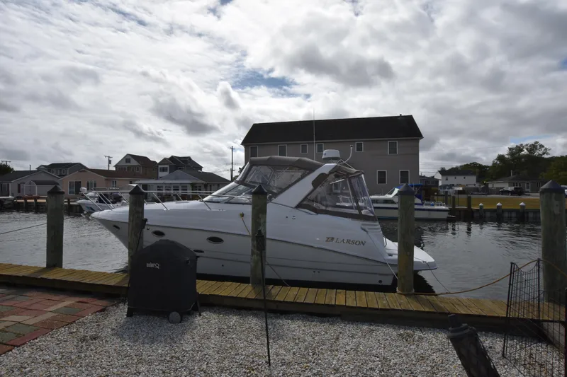 Slide: The Image of 2001 Larson Cabrio 330 boat docked at a marina under cloudy skies. - 1