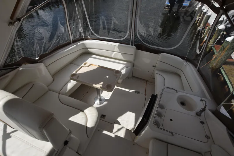 Slide: The Image of 2001 Larson Cabrio 330 boat interior with seating and table, docked by the water. - 12