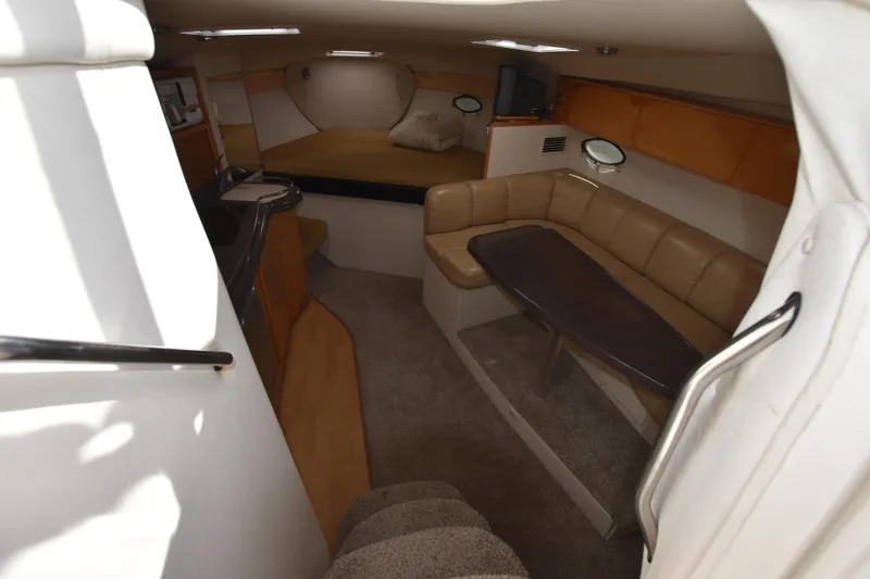 Slide: The Image of 2001 Larson Cabrio 330 cabin interior with seating, table, and bed. - 17