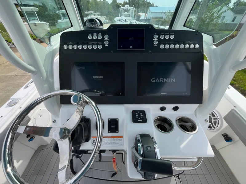 Slide: The Image of 2023 Everglades 253 Center Console boat dashboard with Garmin displays and steering wheel. - 16