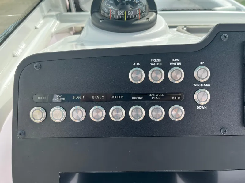 Slide: The Image of Control panel of 2023 Everglades 253 Center Console boat with various switches and compass. - 17