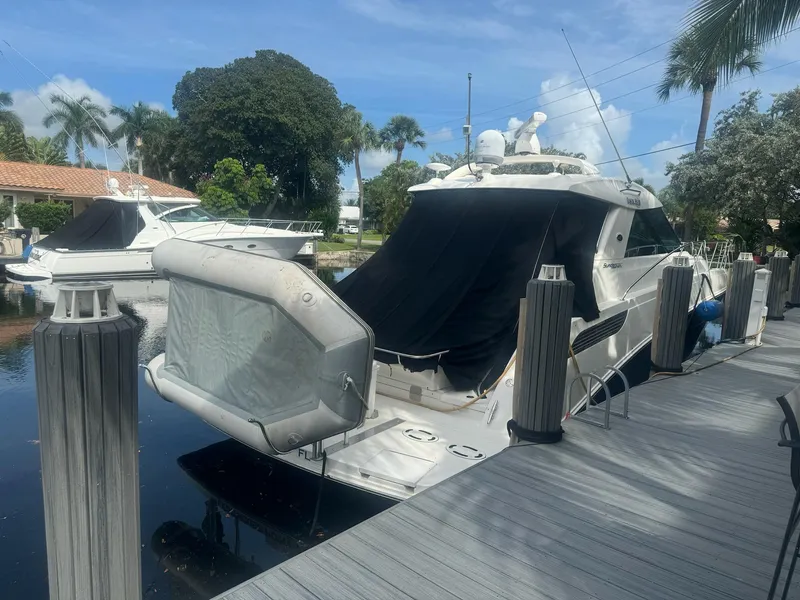 Slide: The Image of 2012 Sea Ray SUNDANCE yacht docked by a wooden pier, surrounded by lush greenery. - 25