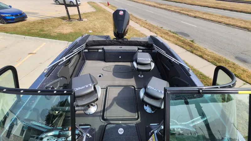 Slide: The Image of 2025 Lund 189 Tyee GL boat interior with seating and motor, parked near a road. - 5