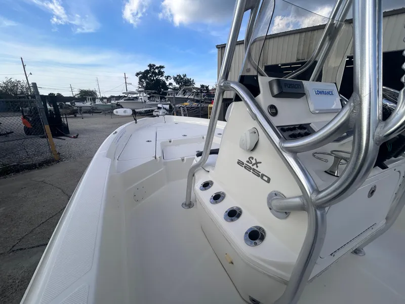 Slide: The Image of 2013 Skeeter SX2250 boat with console and rod holders, docked outdoors under a blue sky. - 17