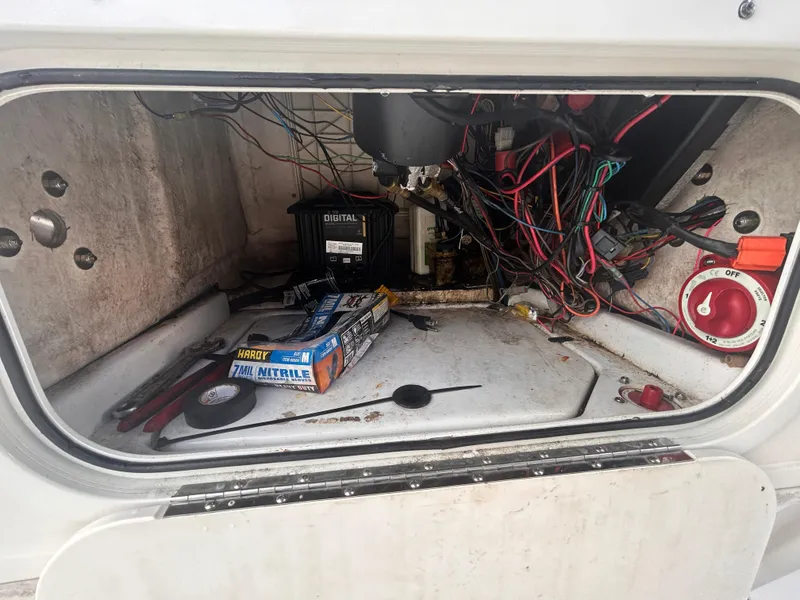 Slide: The Image of 2013 Skeeter SX2250 boat compartment with wiring, tools, and battery. - 21