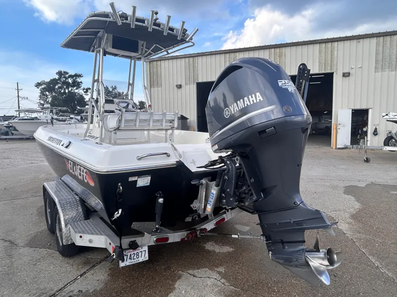 Slide: The Image of 2013 Skeeter SX2250 boat with Yamaha outboard motor on trailer, parked outside a warehouse. - 4